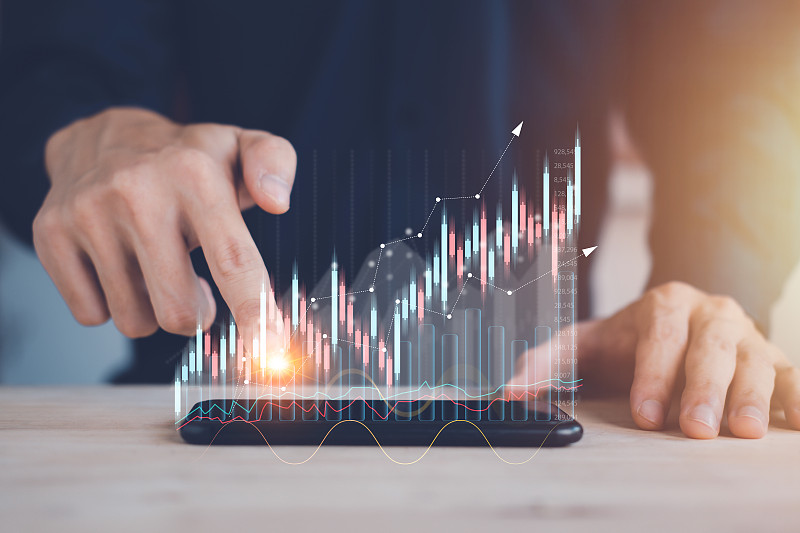 商人用智能手机触摸股票图或加密货币图的全息图。规划和战略概念的统计图和图表增长图。成功的经营理念。