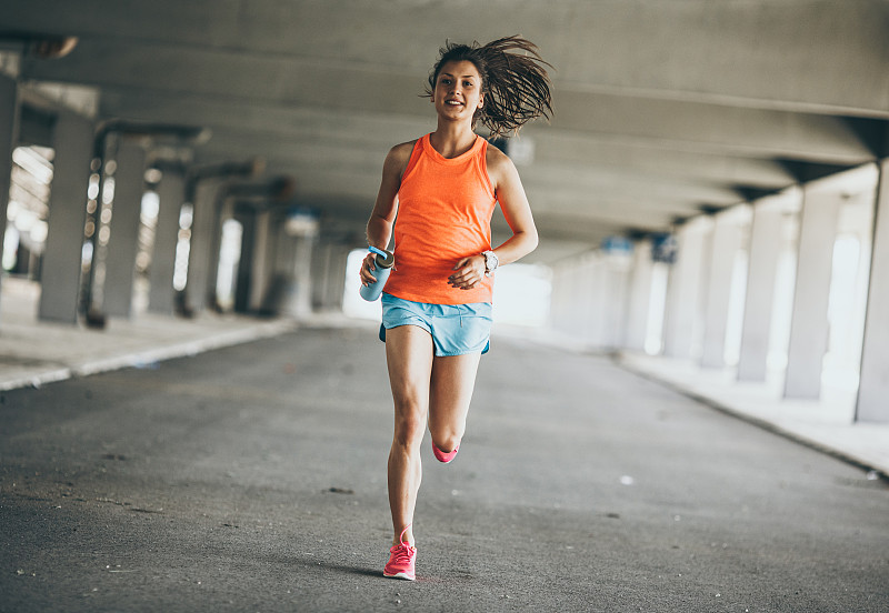 女性跑步者慢跑槽停车场。健身和慢跑的概念。
