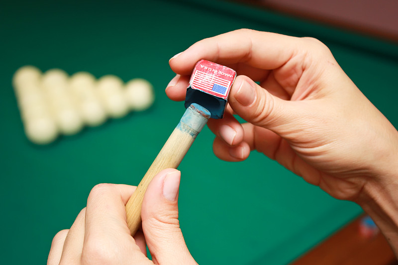 台球运动员用粉笔擦球杆。台球游戏的细节。