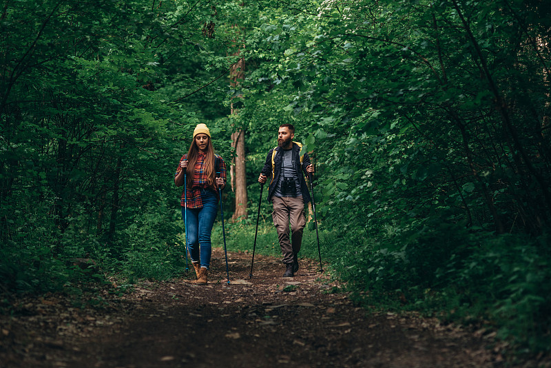 两个徒步旅行者在背着背包的情况下使用登山杖