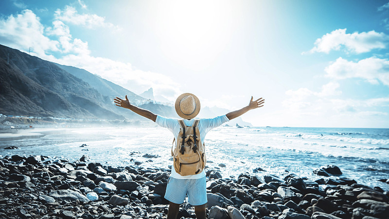 快乐的人与手臂在海滩上享受自由-背包远足庆祝户外成功-蓝色过滤器