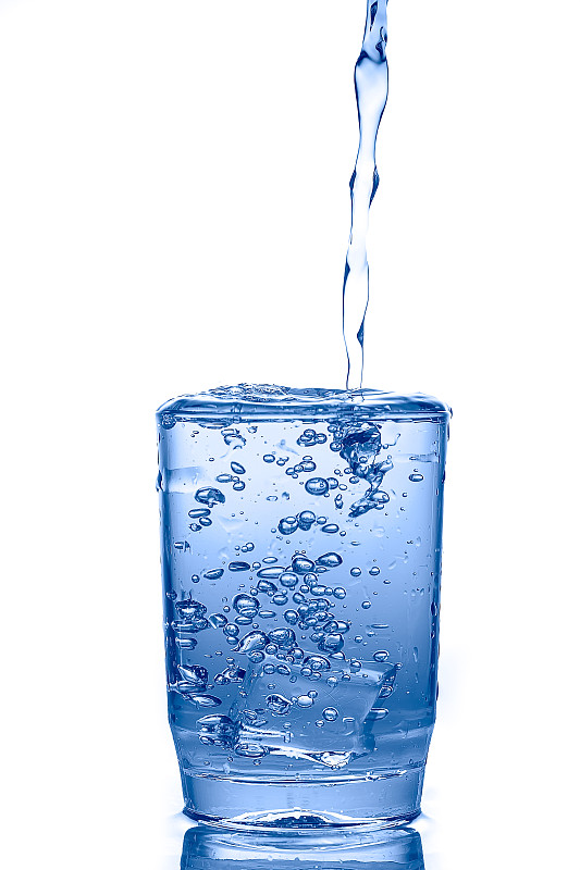 将水倒进白色背景下隔离的玻璃杯中。