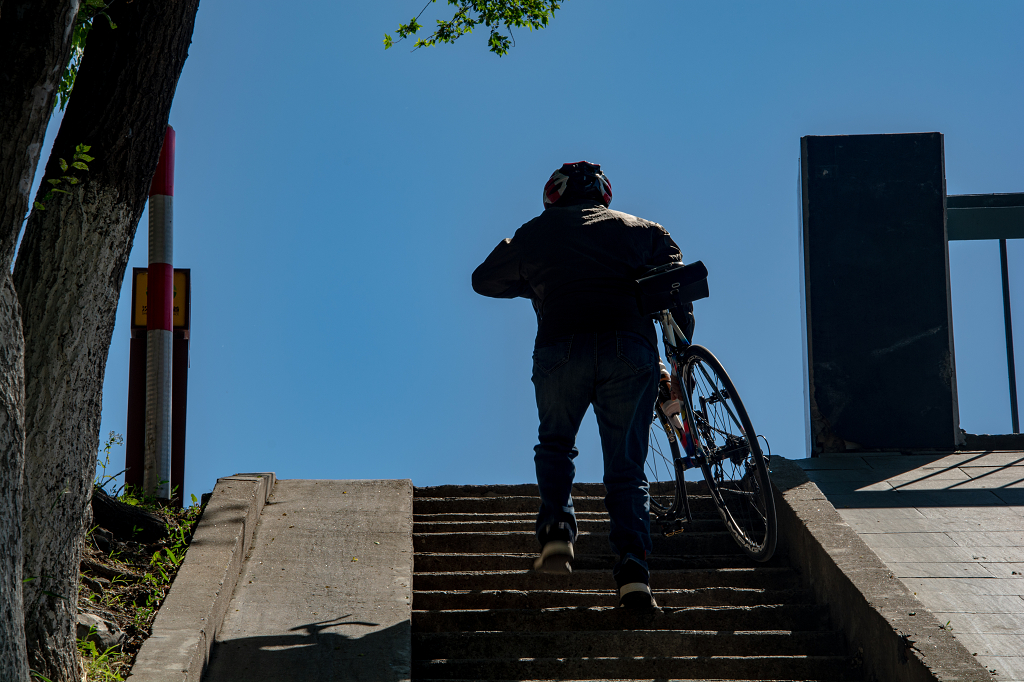 一位骑行男士正抬着自行车沿着楼梯向上走