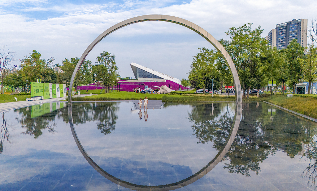 两孩子在水池里戏水建筑物和一个半圆形景观倒影在水面上