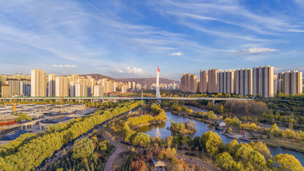 俯瞰西宁湟水河蓝天白云高楼林立河道中金黄色的树林