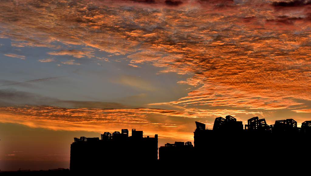 高楼的剪影后的朝霞染红了整个天空的云彩