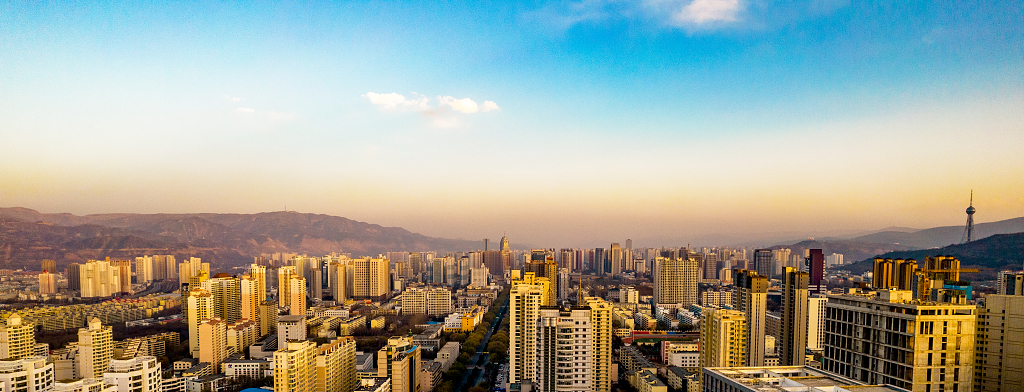 蓝天白云下傍晚的霞光把城市高楼大厦染成了金黄色