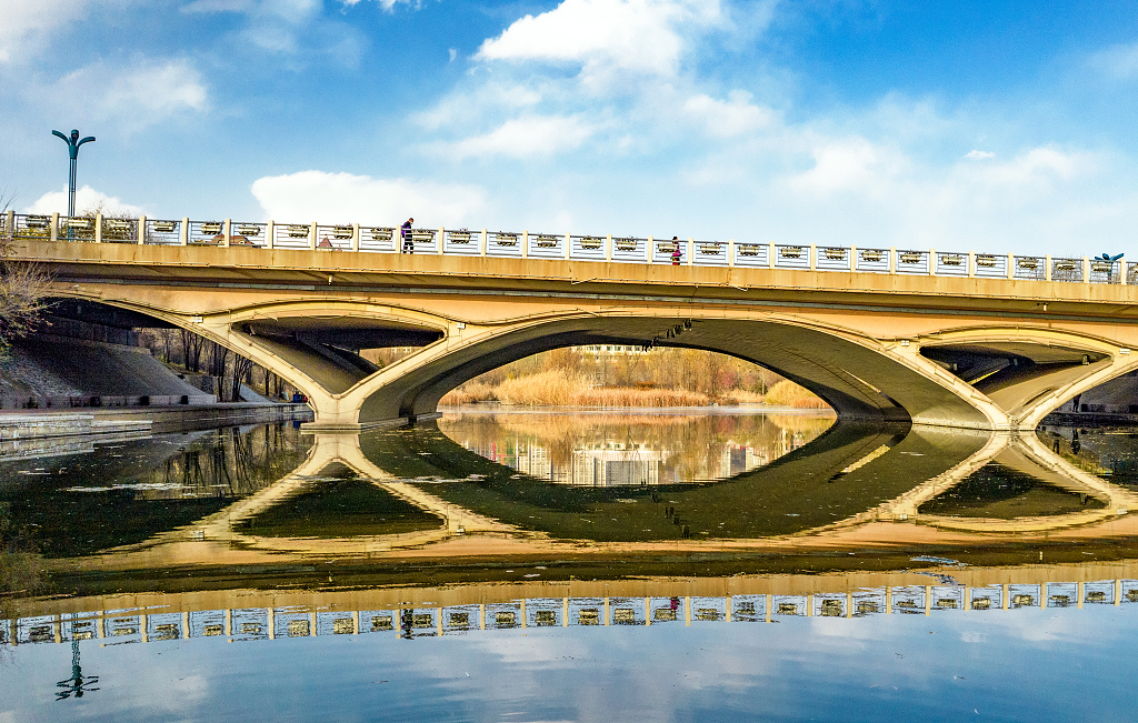 初冬的傍晚蓝天白云阳光照亮了大桥并倒影在水面上