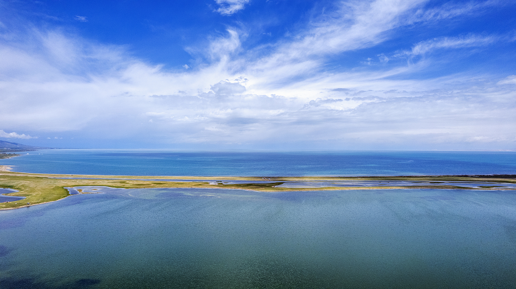 航拍蓝天白云下青海湖蓝色的湖面和黄色的沙路