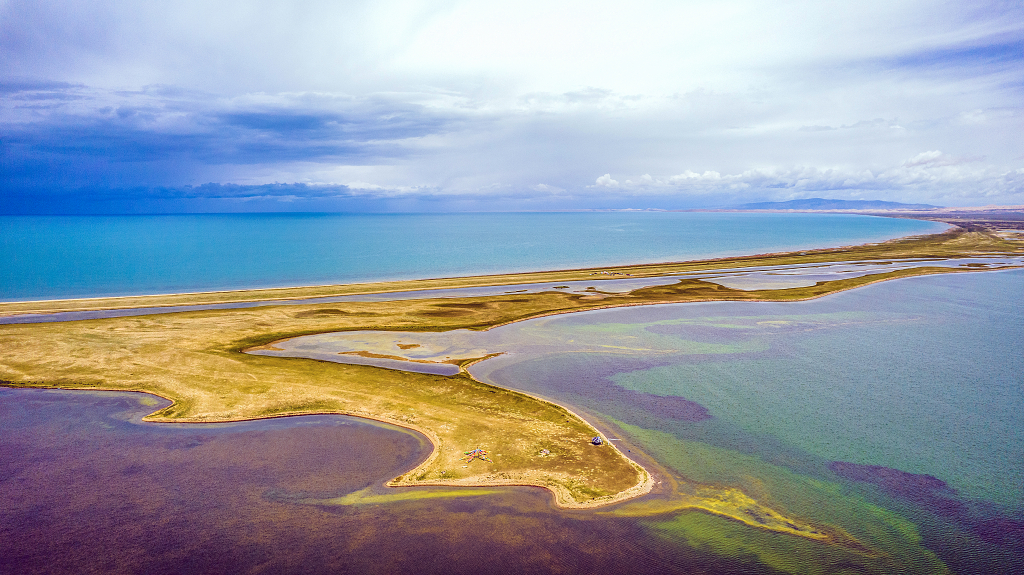 秋日的蓝天白云下青海湖湖面上五颜六色和黄色的沙路