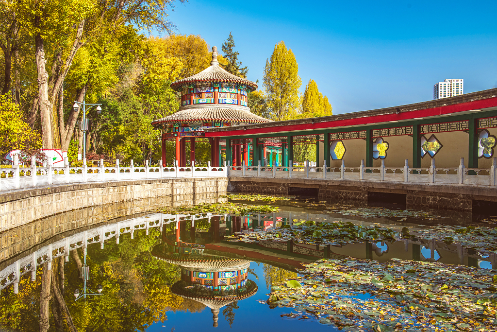 晴朗的秋日公园里一条古建筑长廊倒影在水中