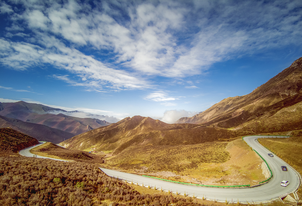 初冬时节蓝天白云下黄色的山峰和一条盘山公路