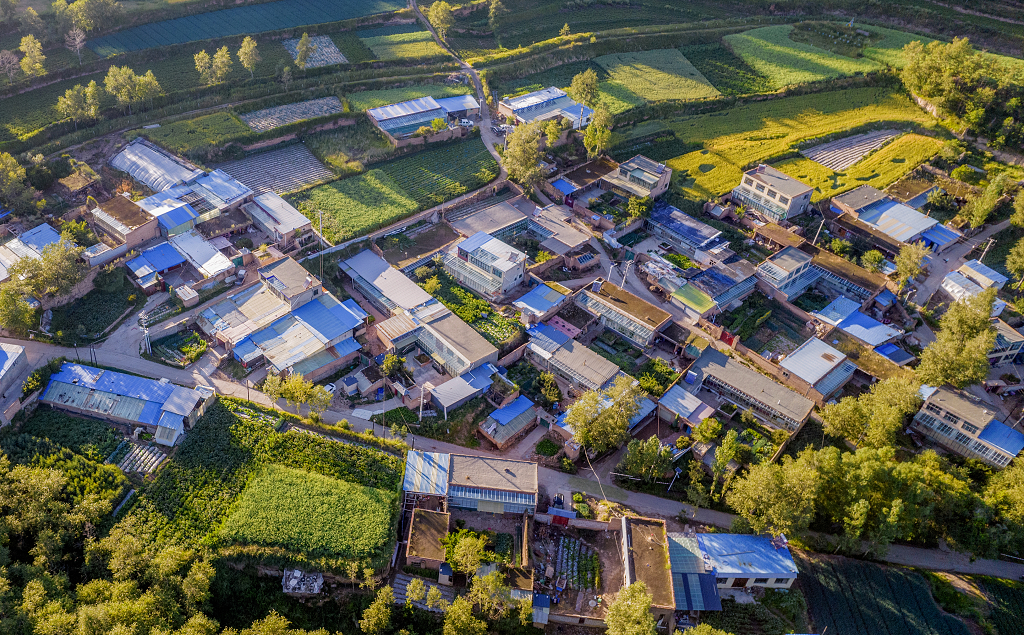 秋日的夕阳下航拍一圈圈梯田环绕的小山村的树木和农作物