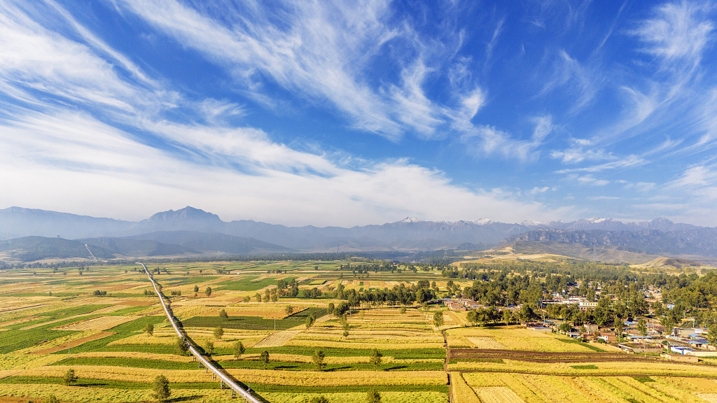 蓝天白云下航拍农田里成熟的农作物和村庄及工业长廊