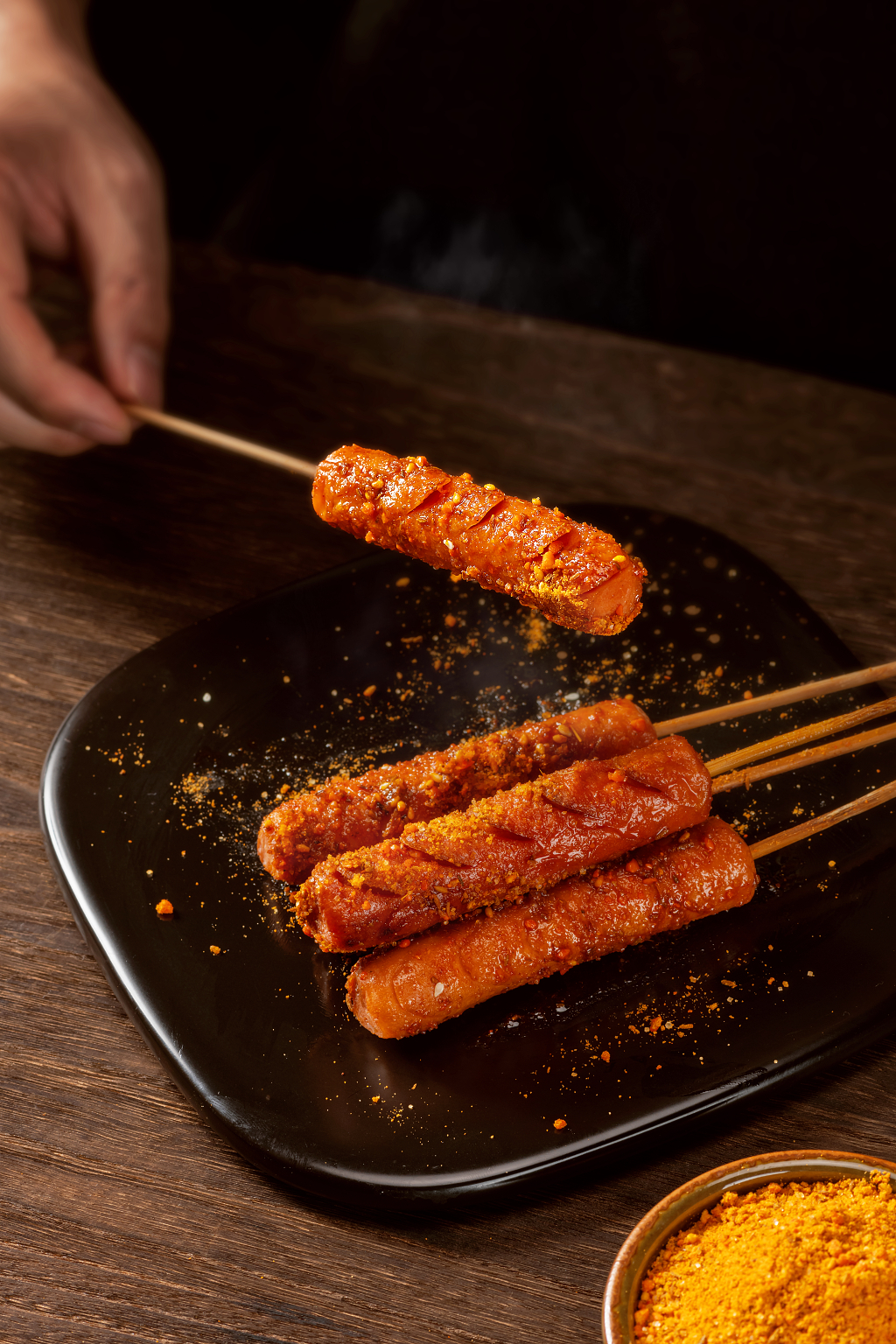 手拿一个烤熟的烤肠美食摄影