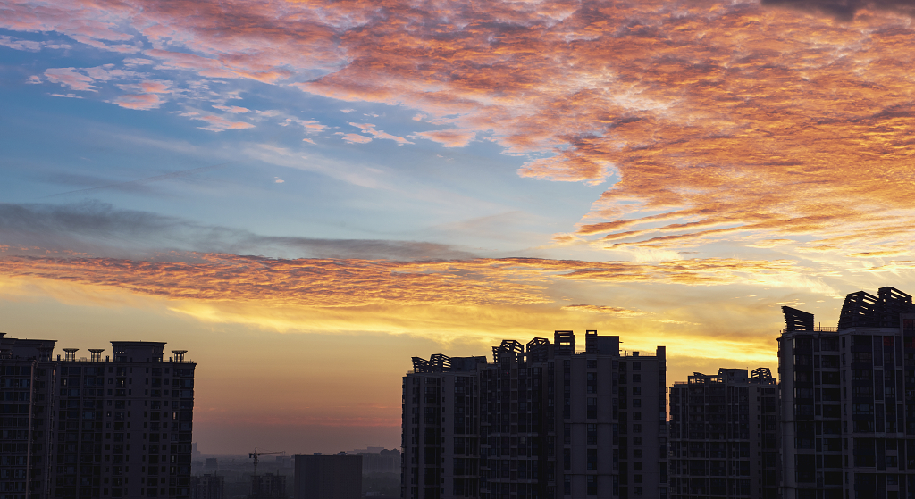 夏日的日出时分天空火烧云下城市高楼的剪影