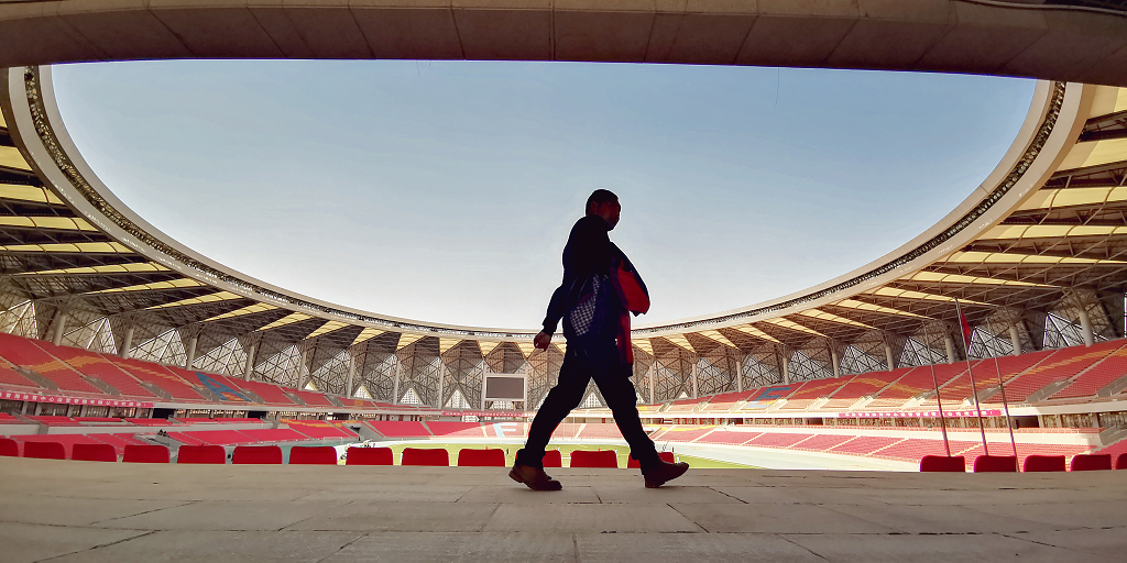 仰拍体育馆半圆形的屋顶和座椅前一位行人走过