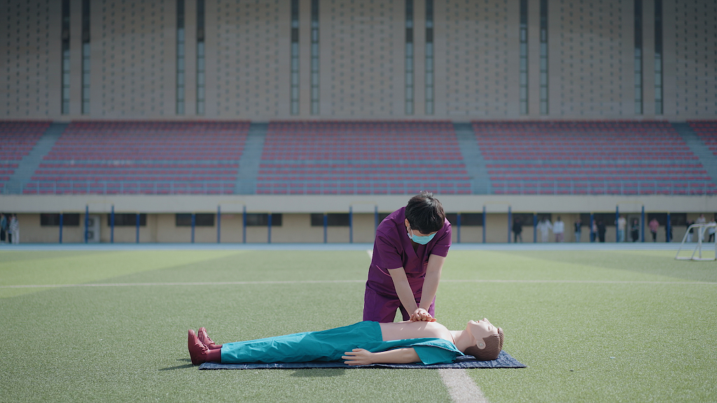 操场草地女护士给病人心肺复苏急救