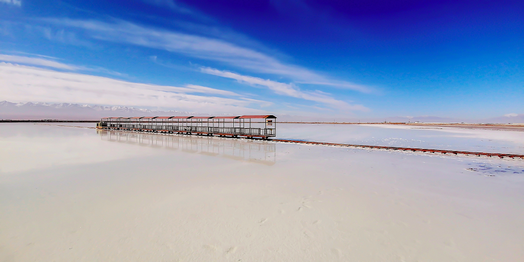 蓝天白云下一辆小火车倒影在盐湖湖面上