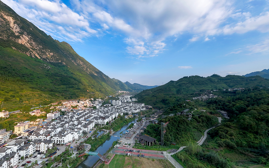 日出时分蓝天白云下大山深处的小镇房屋和河流