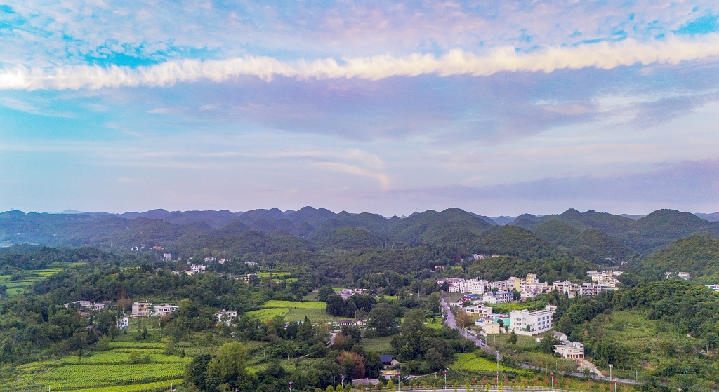 夏日的傍晚航拍天空的彩云及晚霞下的小山村