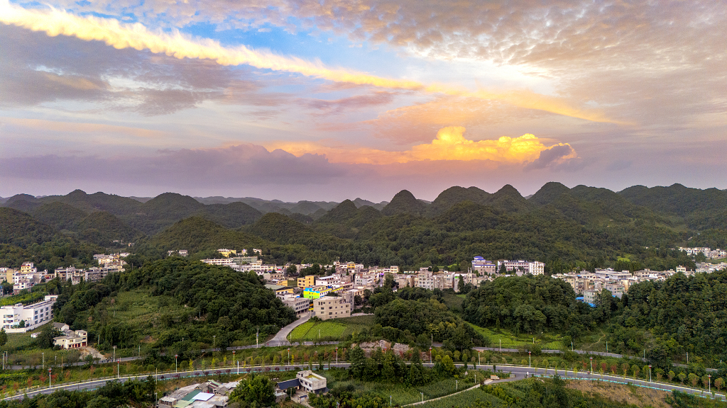 夏日的傍晚航拍天空的彩云及晚霞下的小山村