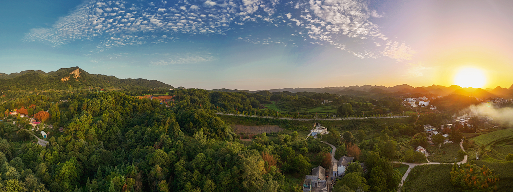 夏日的清晨航拍群山间的薄雾初升的太阳及小山村里的炊烟