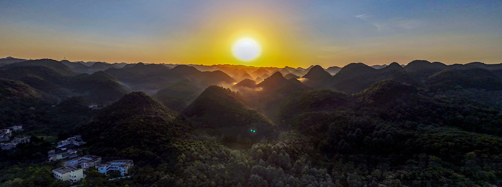 夏日的清晨航拍群山间的薄雾和农舍及初升的太阳