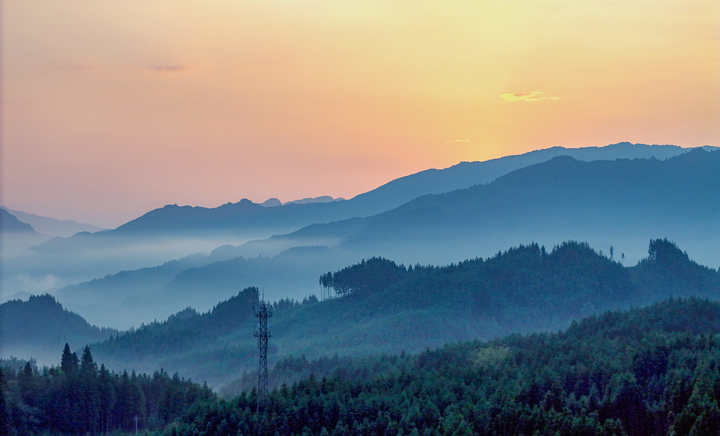 夏日的日出时分航拍橘黄色的天空和大山间的云雾