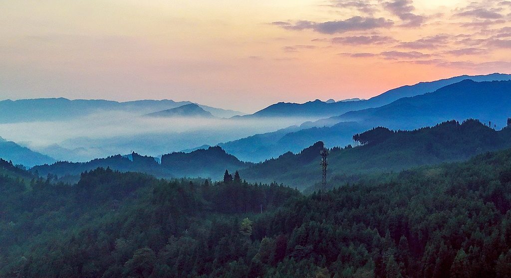 夏日的日出时分航拍橘黄色的天空和大山间的云雾