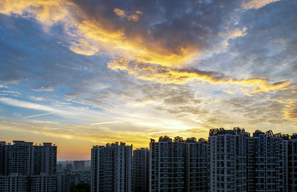 夏日的日出时分城市上空的金黄色的彩云和建筑物剪影