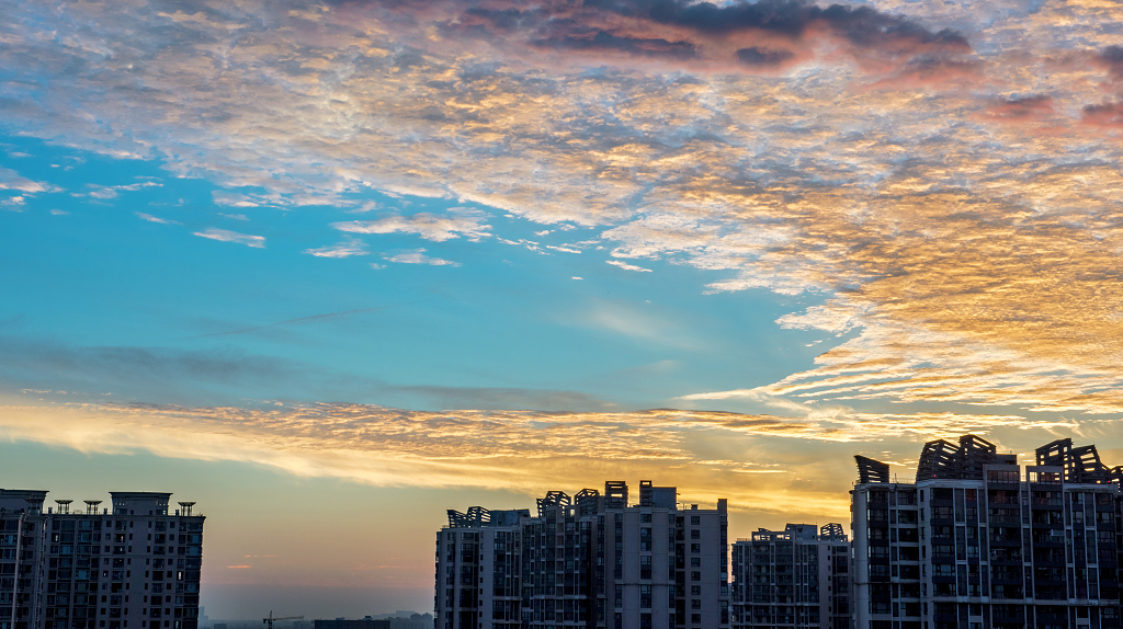 夏日的日出时分城市上空的金黄色的彩云和建筑物剪影
