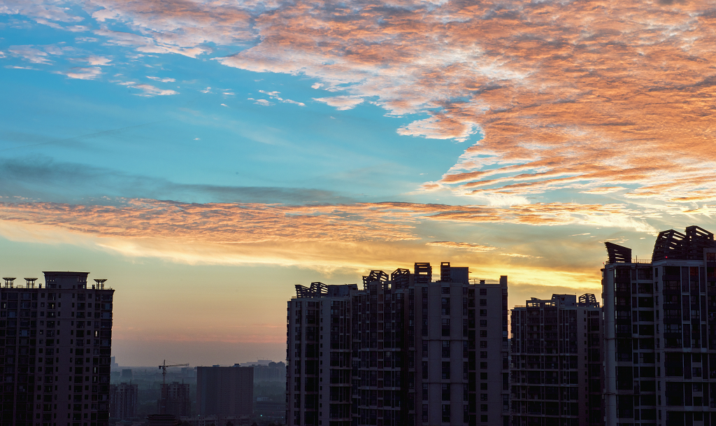 夏日的日出时分城市上空的金黄色的彩云和建筑物剪影