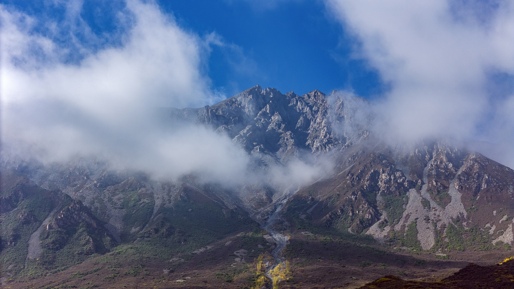 秋天航拍云雾缭绕的山峰和山下金黄色的树木