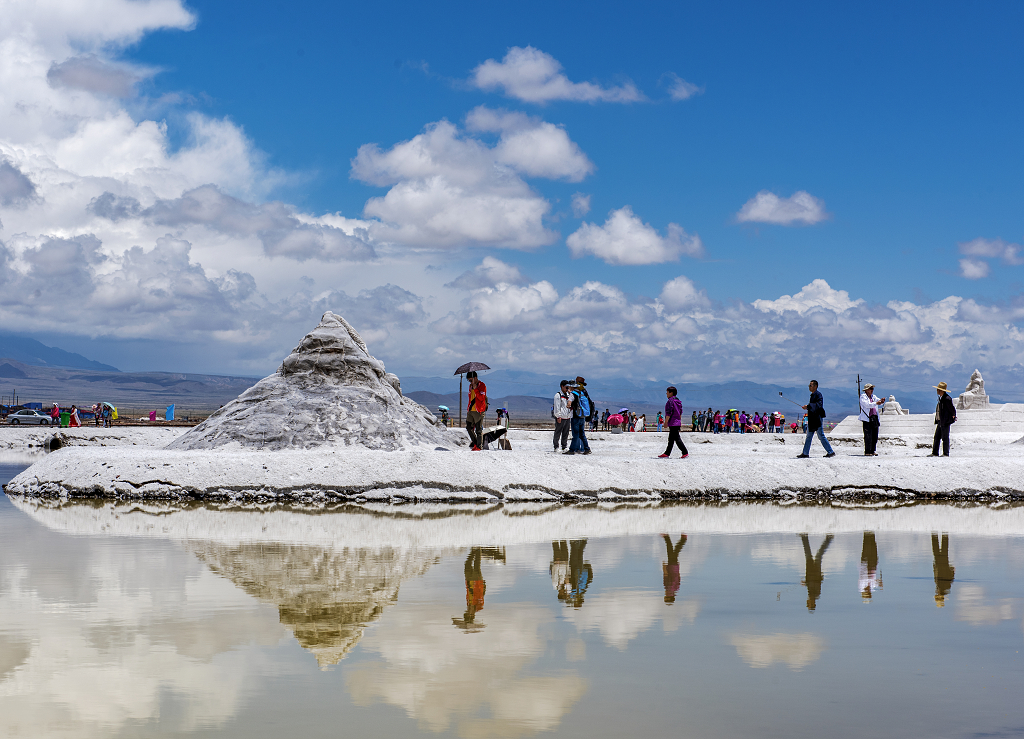 晴朗的夏日蓝天白云下游客在茶卡盐湖上拍照留念