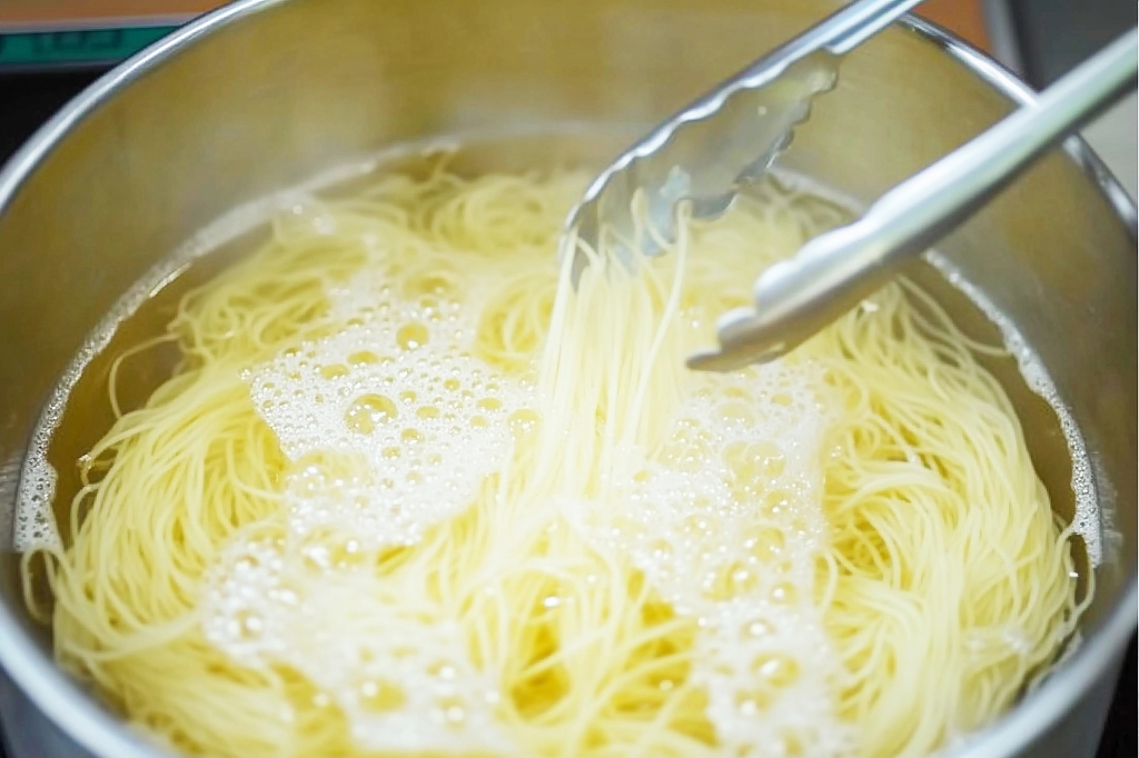 不锈钢锅中正在烹煮的黄色细长面条AI