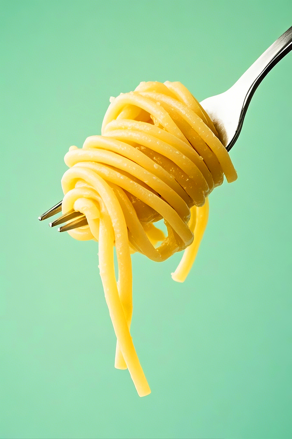 绿色背景下叉子卷起金黄色的细长意大利面AI