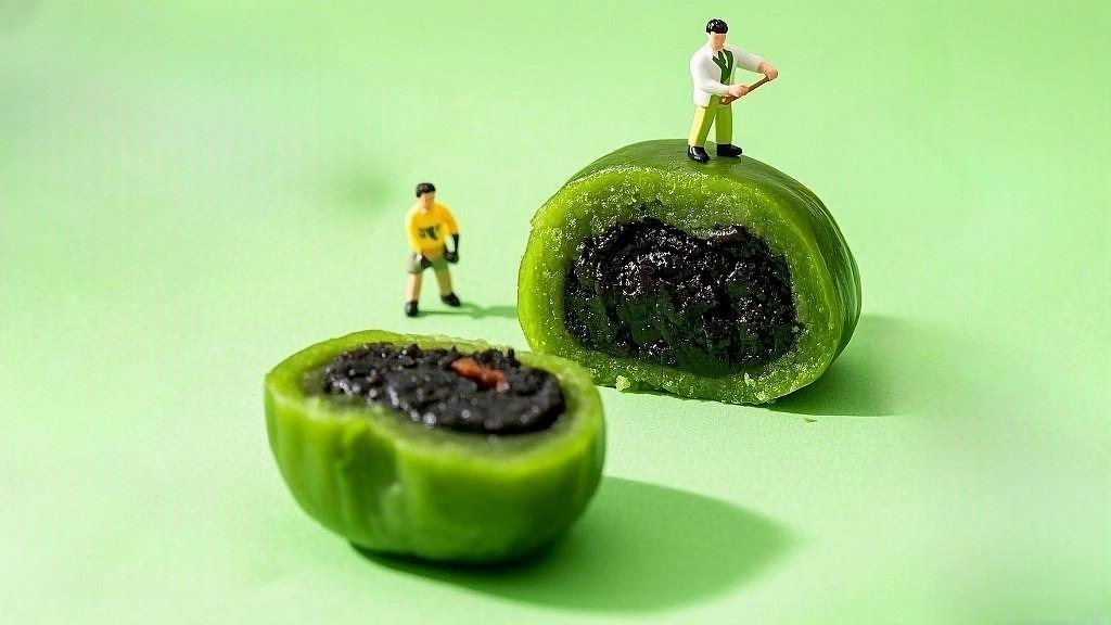 绿色背景下微缩人偶围绕切开芝麻馅的清明节青团AI