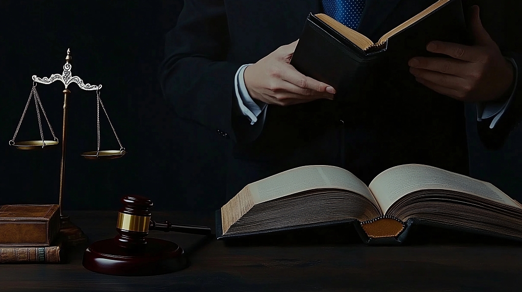 暗色背景中人物手持书本旁边摆放法槌和天平的法律图片AI