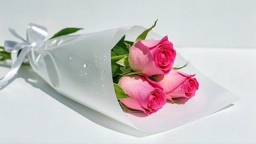 白色包装纸包裹着带水珠的粉色玫瑰束	AI