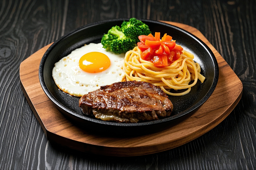 黑色铁盘上放着牛排煎蛋意面西兰花的丰盛套餐	AI
