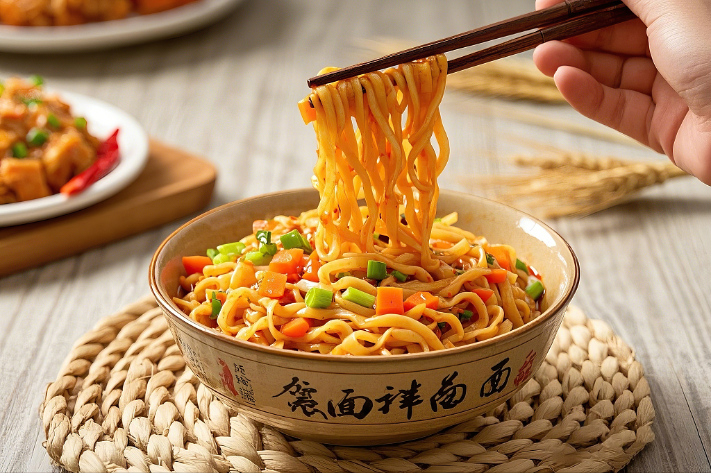 拌面美食面条编织垫上有字的碗里筷子夹起胡萝卜葱花拌面热干面	AI