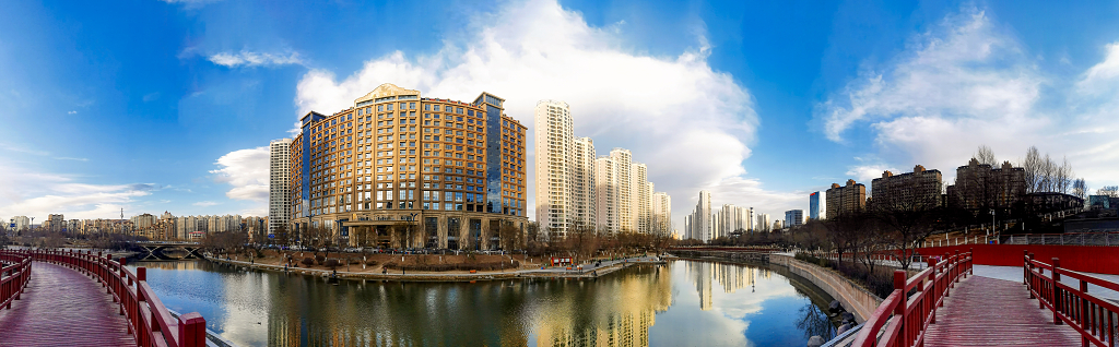 初春的傍晚霞光把城市建筑物染成了金黄色并倒影在水面上