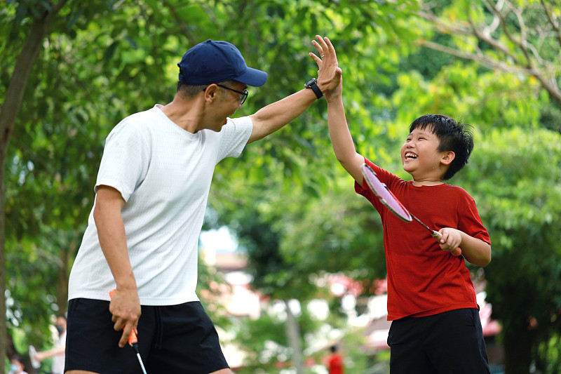 父子俩在公园里击掌，打羽毛球