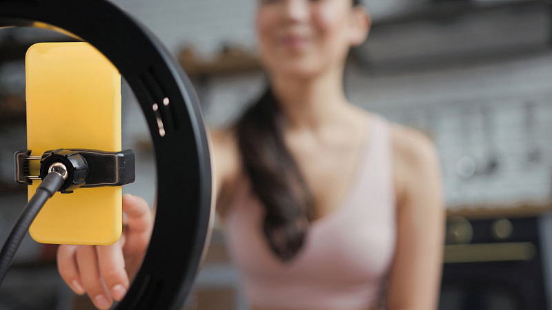 健康的亚洲瑜伽女人坐在莲花的位置和做在线瑜伽课。专注于手机。合十礼