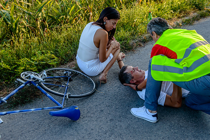 一个骑自行车的人在路上发生了可怕的车祸，当时一男一女正试图帮助他。