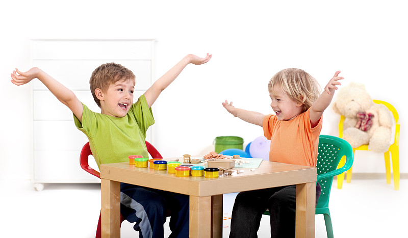 两个小男孩玩得很开心，玩橡皮泥