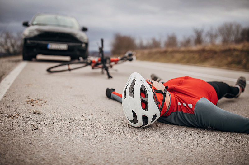 一个骑自行车的人在路上被一辆汽车撞了