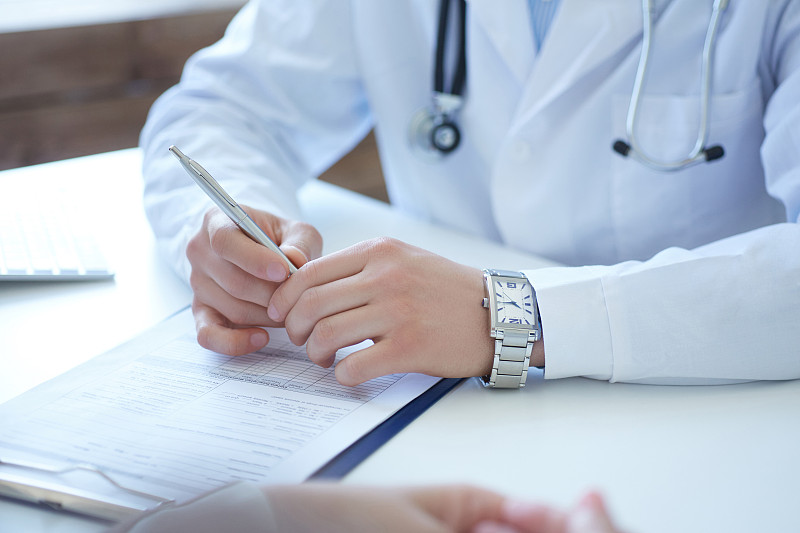 医生在办公室与病人交谈。医生和病人在讨论什么，只是手放在桌子上。医疗保健和医疗理念。