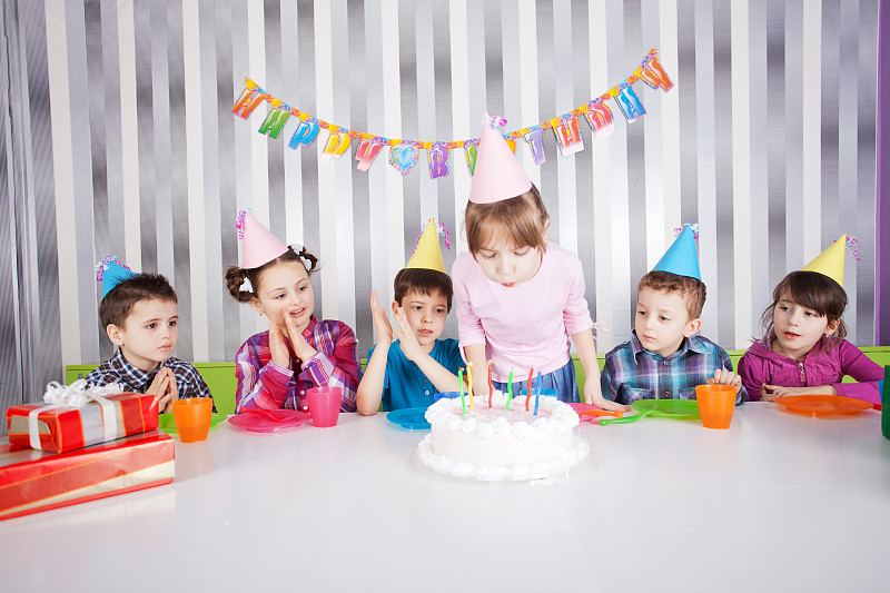 可爱的女孩吹生日蛋糕上的蜡烛。